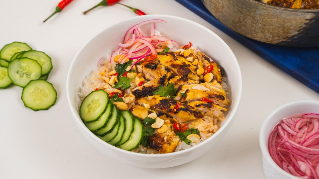 coconut sriracha chicken bowl with cucumbers, pickled red onions, and rice