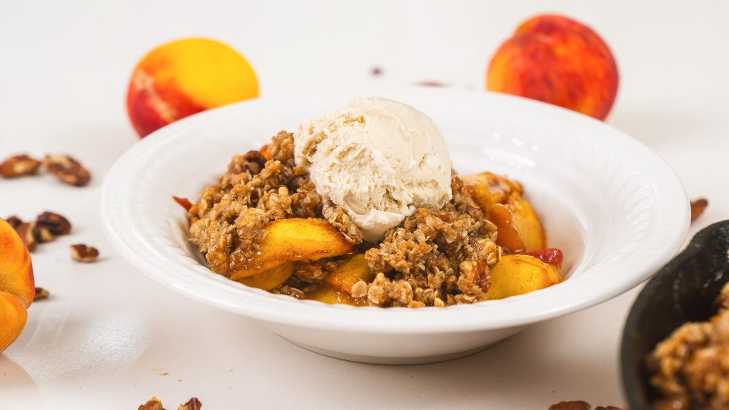 close up shot of peach crisp with ice cream on top