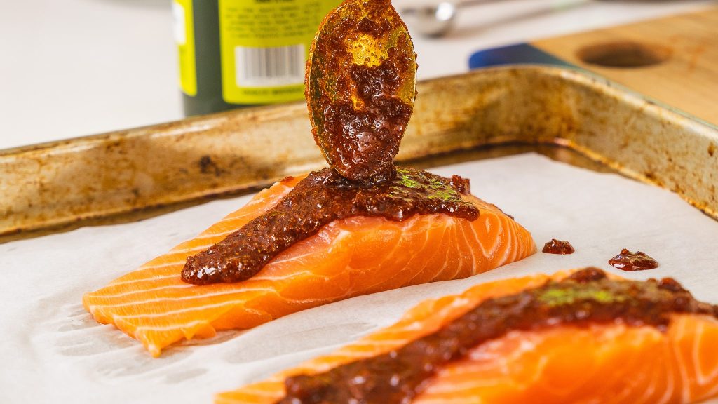 bbq spice rub being poured onto salmon filets