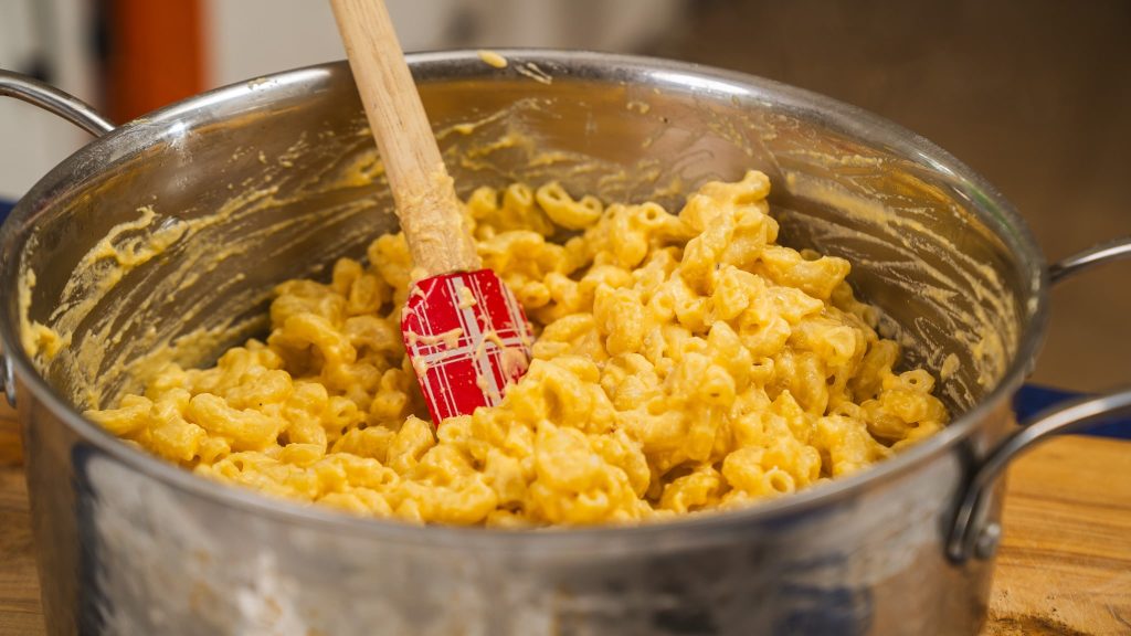 mac and cheese in pot with red spatula