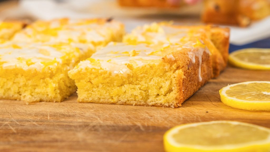 The image shows freshly lemon brownies recipe, topped with a light lemon glaze.