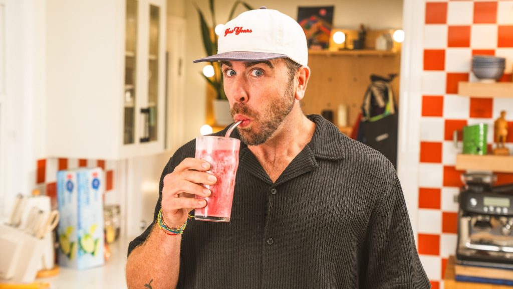 andy hay drinking pink smoothie out of a glass swith a straw