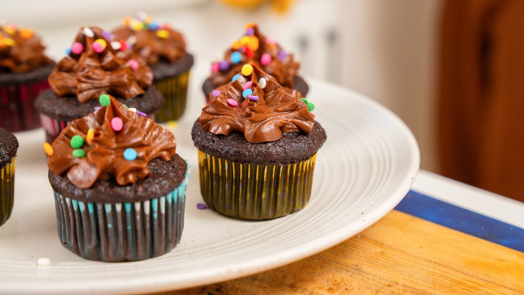 side angle shot of chocolate cup cake with icing and sprinkles