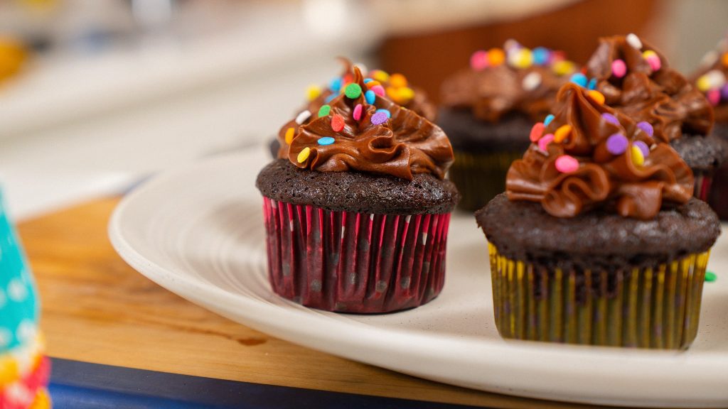 horizontal angle of a chocolate cup cake topped with icing and sprinkles