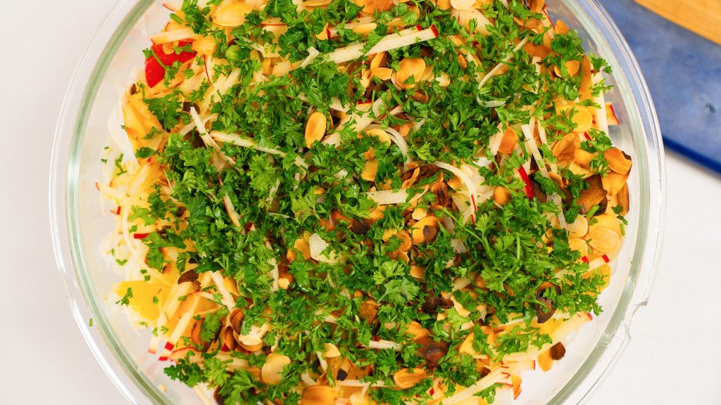 Top down view of glass bowl of salad. Topped with parsely, this orange fennel slaw is refreshing and bright