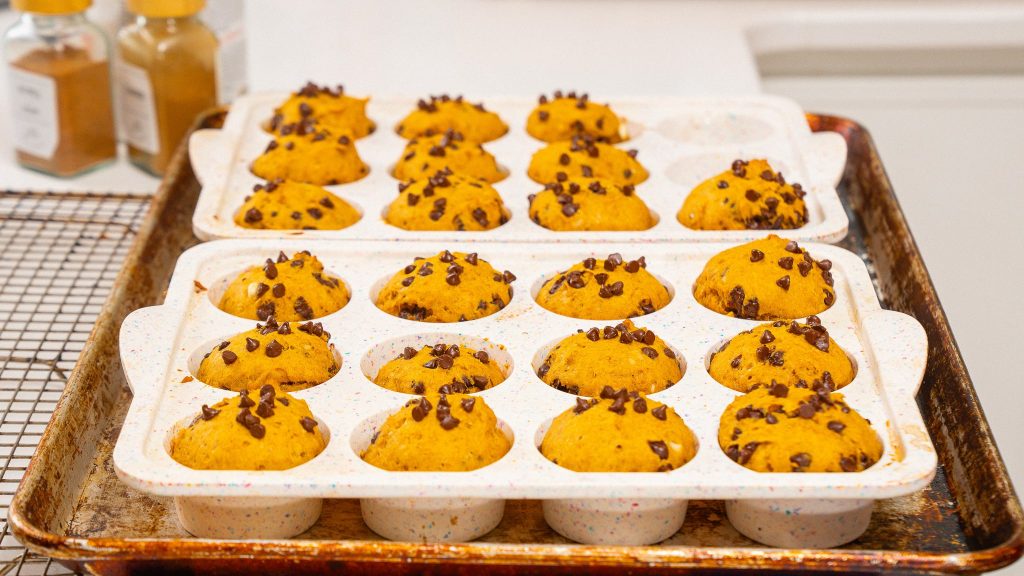 recipe cooling in two speckled trays on a baking sheet, topped with mini chocolate chips.