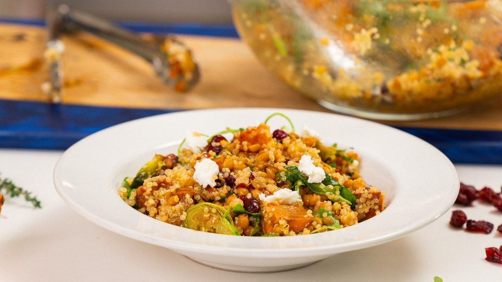 side angle shot of white bowl filled with quinoa, sweet potatos, cranberries