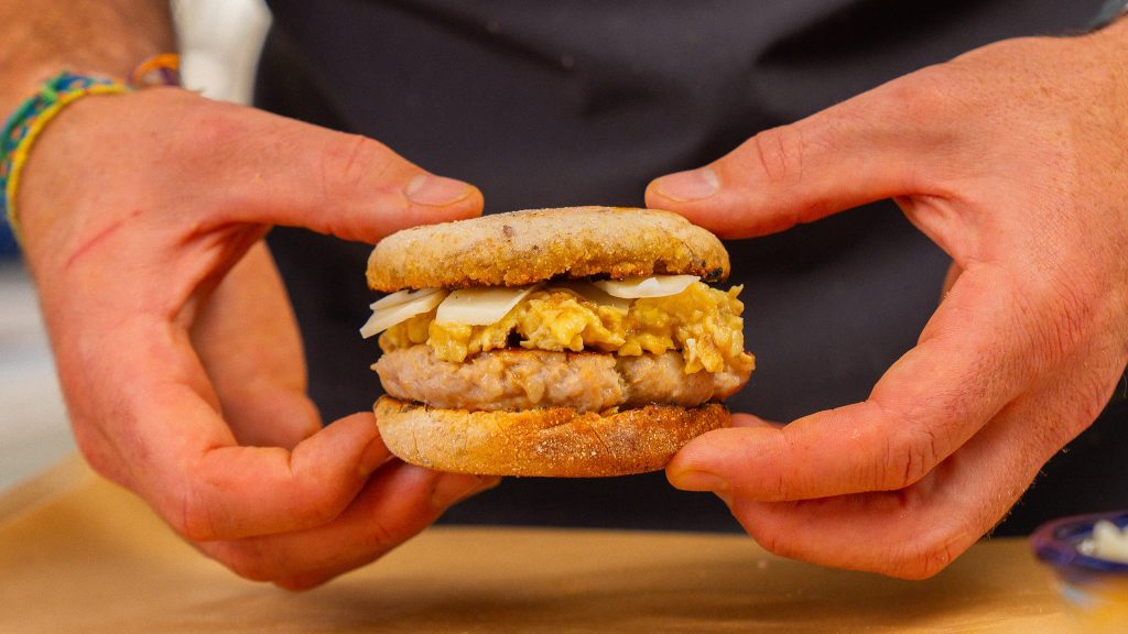 Hands holding a breakfast sandwich.