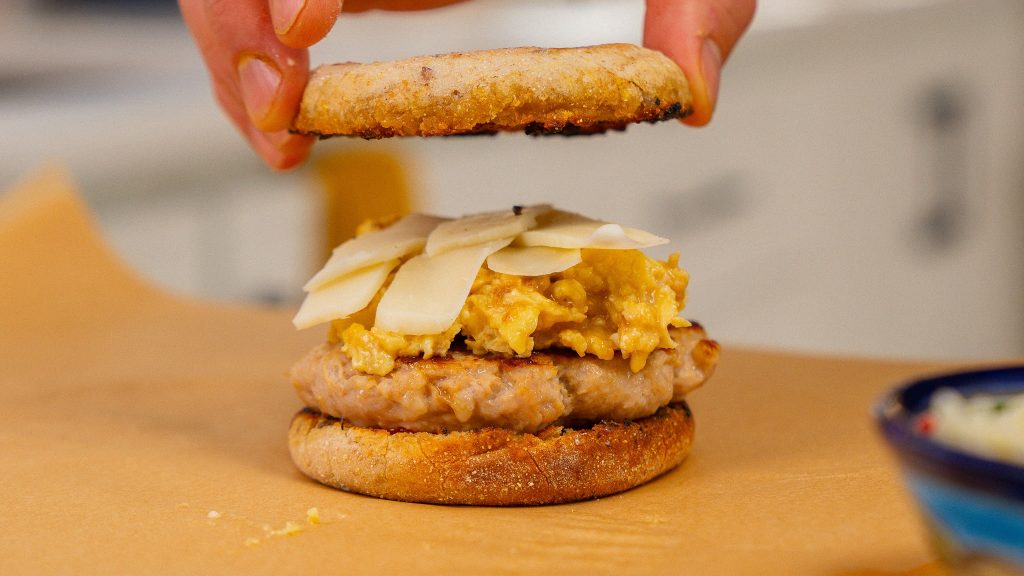 hand placing english muffin top on sandwich