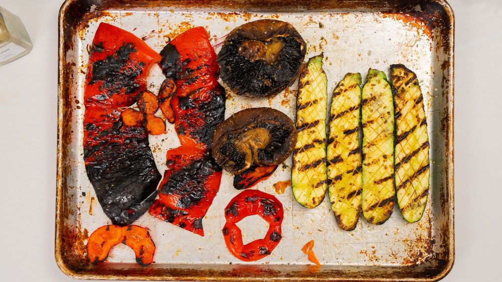 top down view of charred red peppers, portobello mushrooms, and zucchinis.