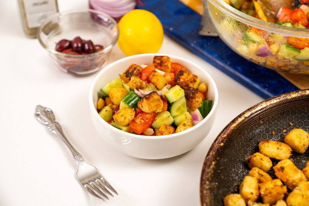 side angle view of greek salad with fork in fore ground and lemon and olives in background