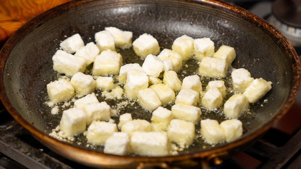 feta cube and coated in cornstarch in a frying pan 