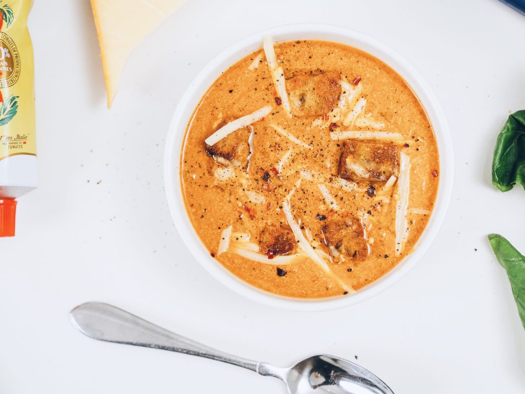 Top down of soup with spoon and tomato paste.