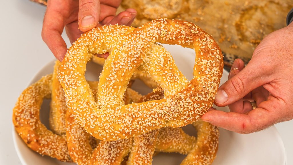 hand holding soft homemade pretzel with other pretzels in background