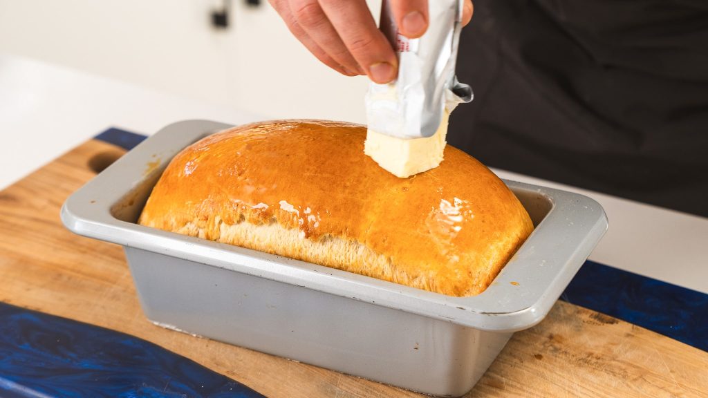 butter being rubbed on top of fresh bread