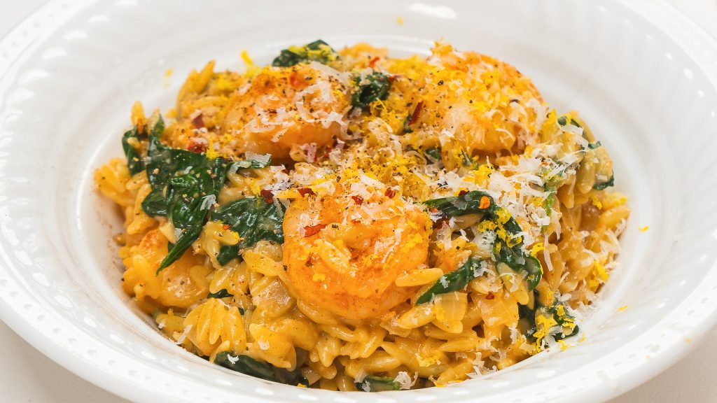 Garlic shrimp pasta in a white bowl with fresh herbs. A shrimp orzo recipe that is delicious and easy!