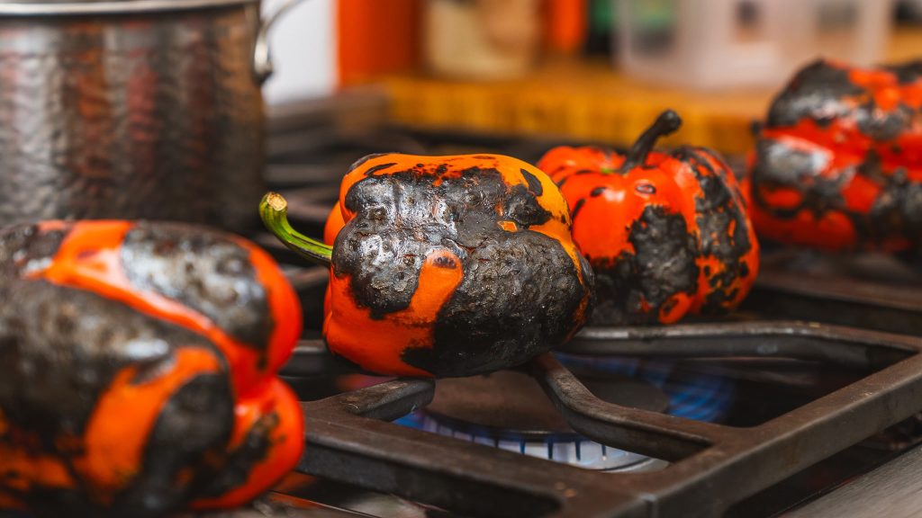 Charred and blistered veggies sitting on a grill top.