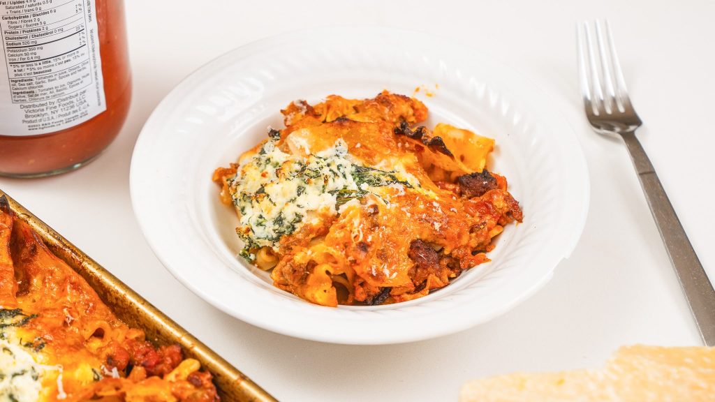 White bowl on counter filled with cheesy sheet pan lasagna.