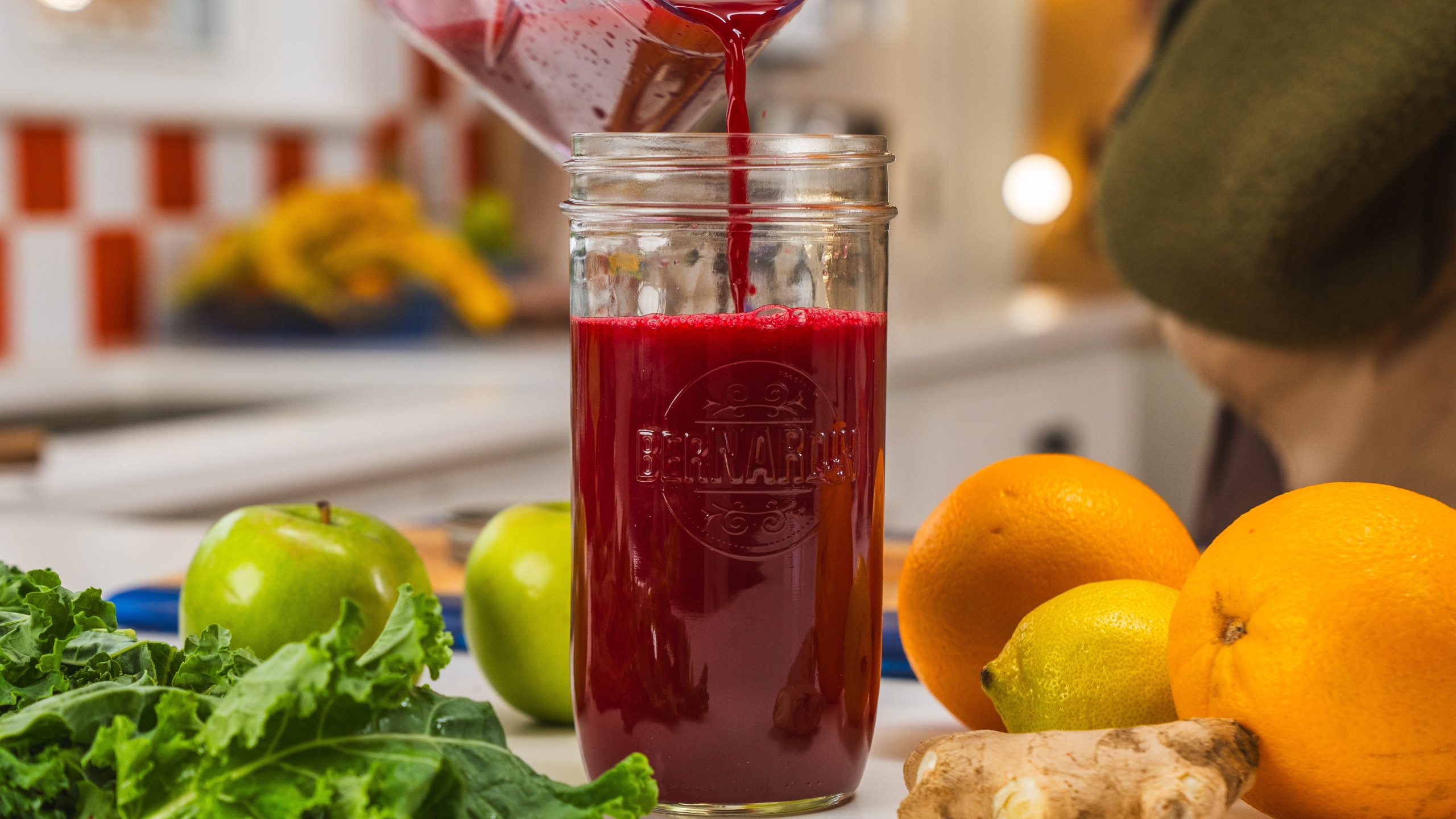 A mason jar filled with a delicious ginger wellness shot including beets, kale and citrus fruit.