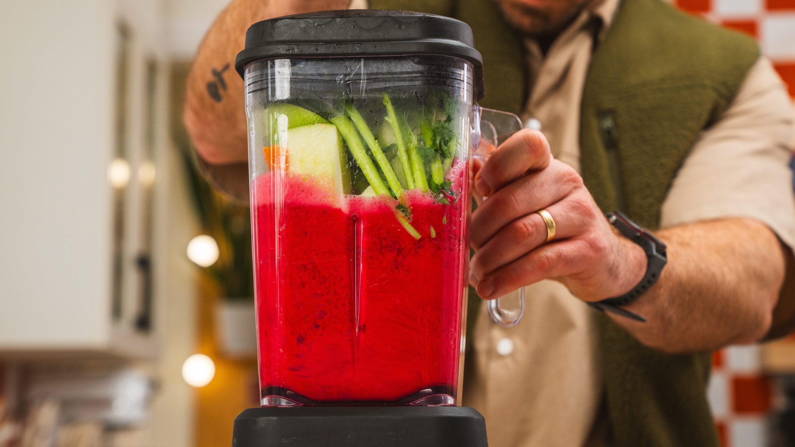 a blender filled with citrus fruit, kale and beets, being zipped up.