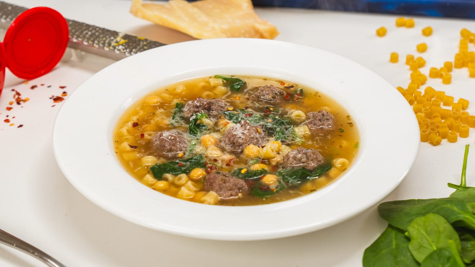 Italian Wedding Soup in a white bowl, sitting on a counter. This Italian wedding soup recipe is warm and delicious.