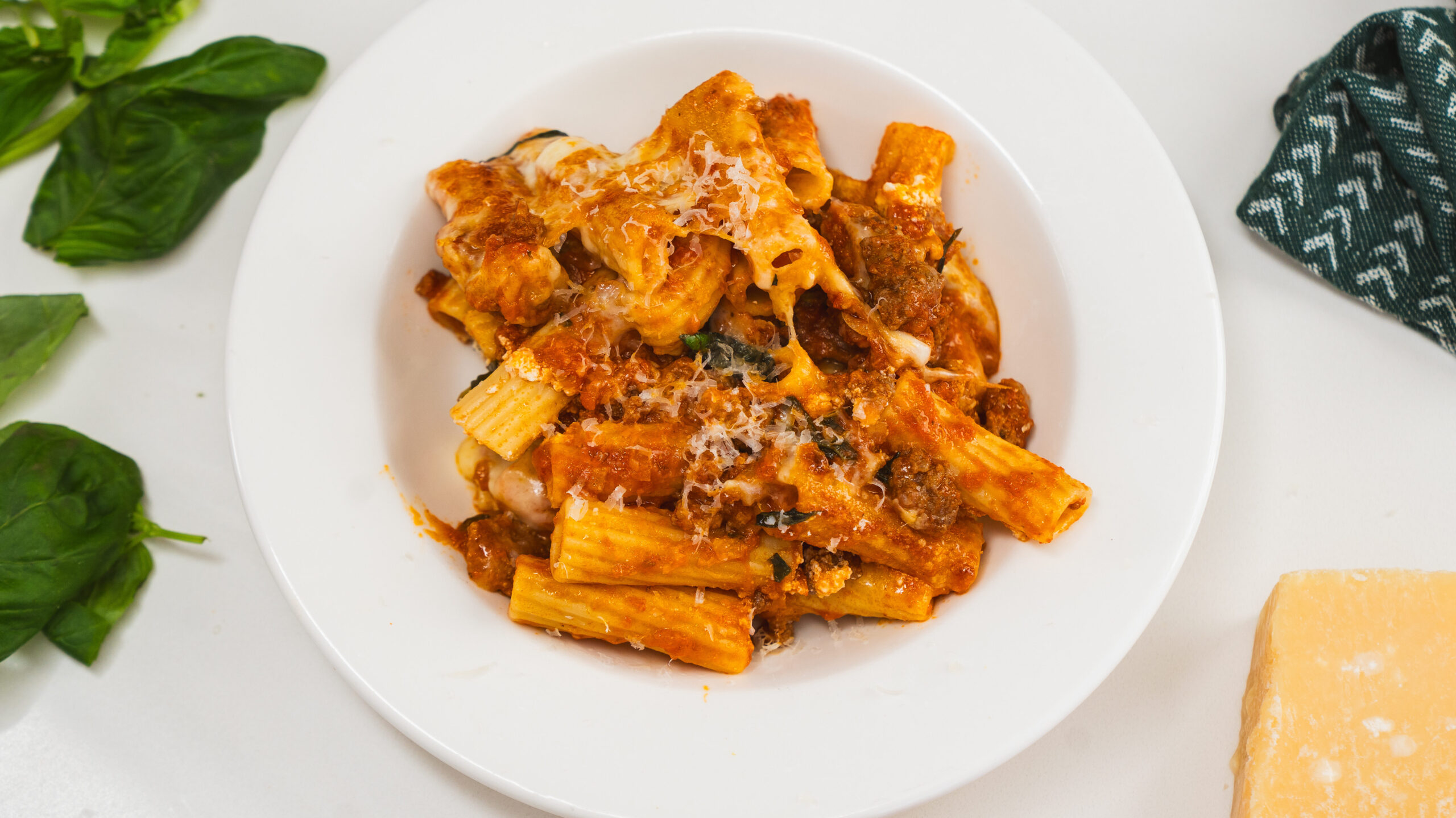 Baked rigatoni in a white bowl with a creamy tomato and ricotta mixture.