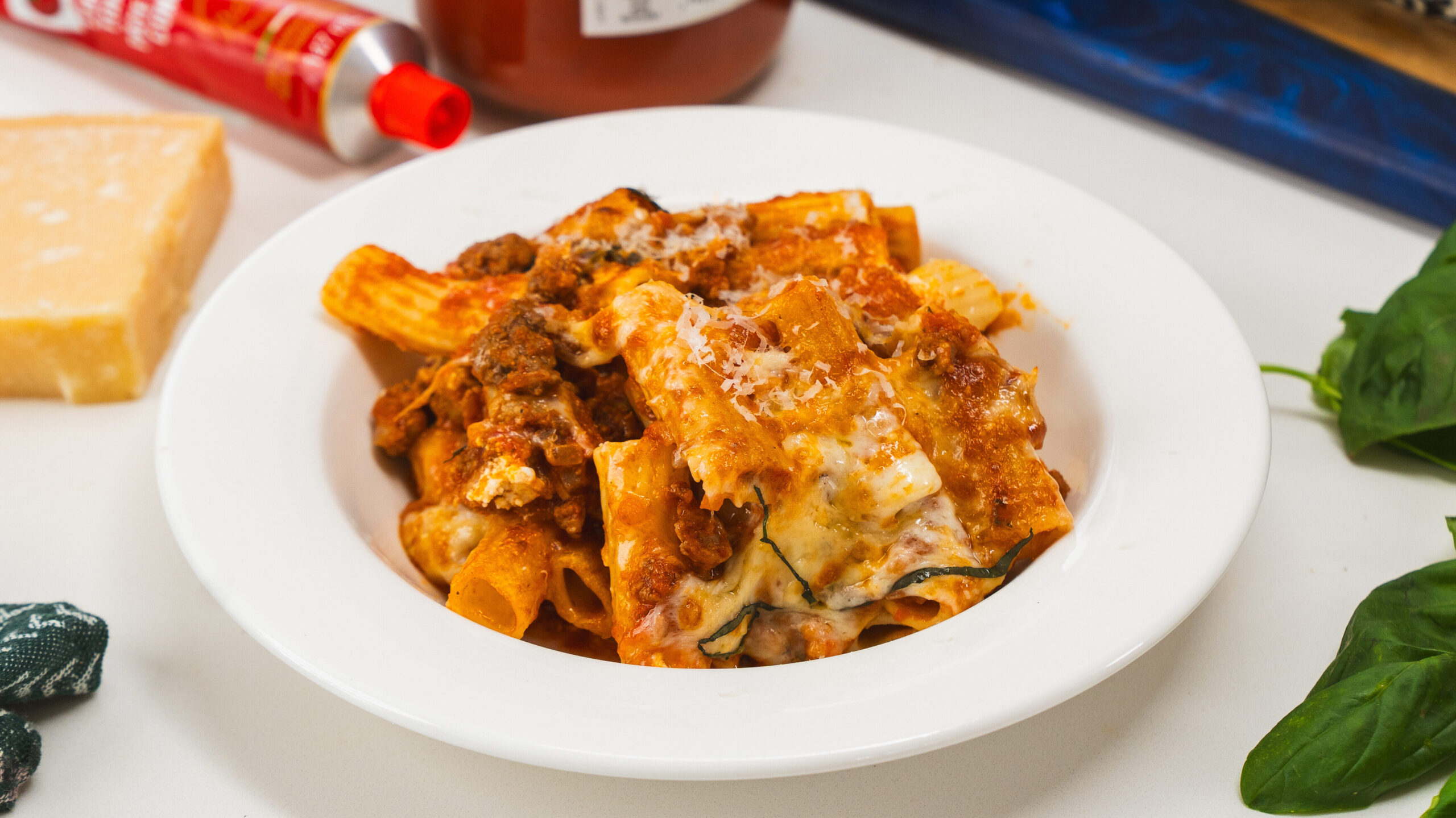 Baked rigatoni in a white bowl with a fork visible to the front.