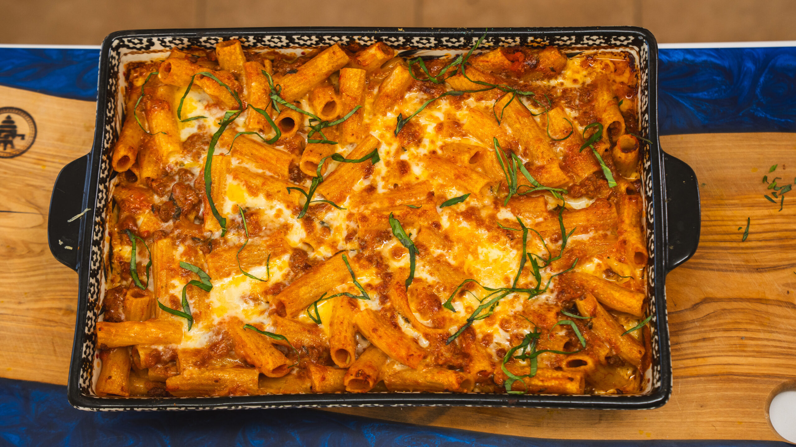 Based rigatoni in a casserole dish with bubbly, melted cheese on top.