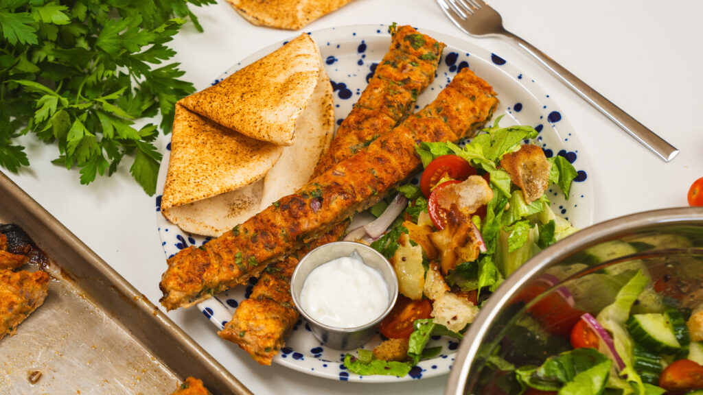 Kofta on a plate with a side salad and pita bread. An easy sheet pan chicken recipe everyone will love.