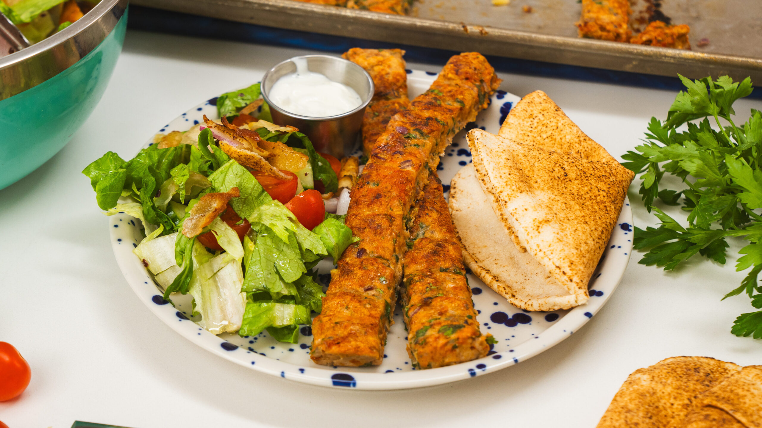 A plate of easy chicken kofta, salad and pita bread. An easy sheet pan chicken recipe.