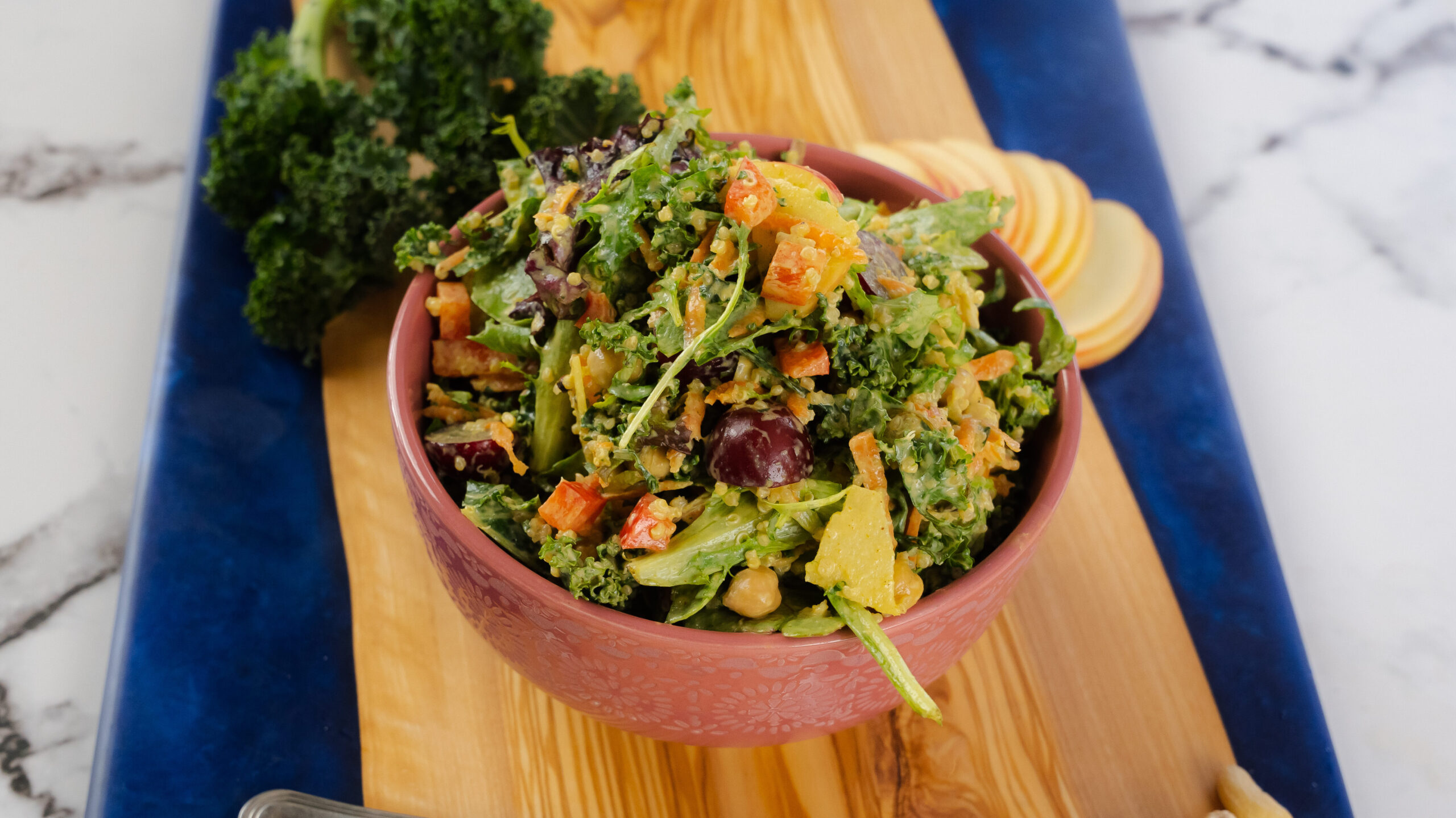 Kale Quinoa Salad in a wood bowl with a fork nearby.