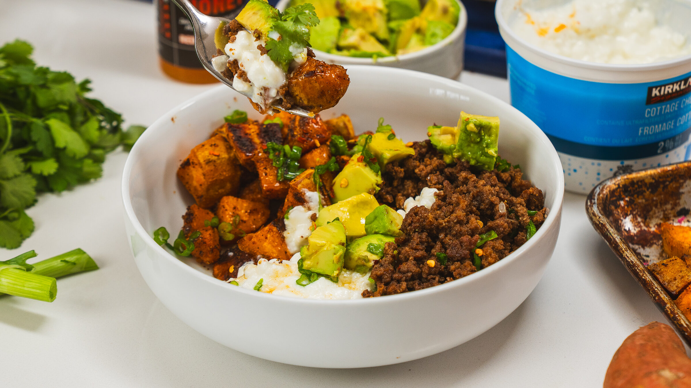 Ground beef protein bowl topped with sweet potato, cottage cheese, avocado and hot honey.