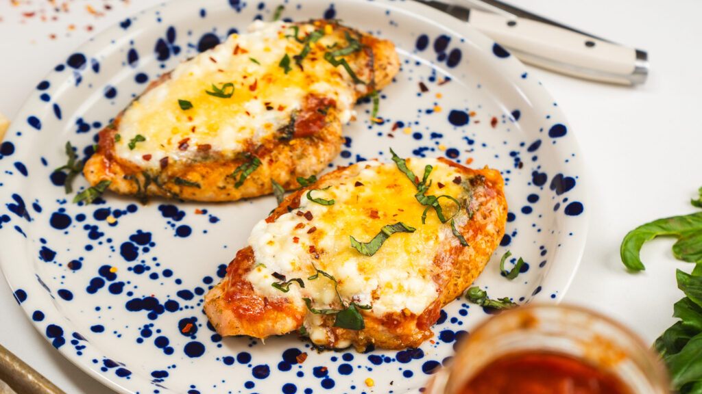 High protein chicken parmesan on a platter with marinara and cheese.