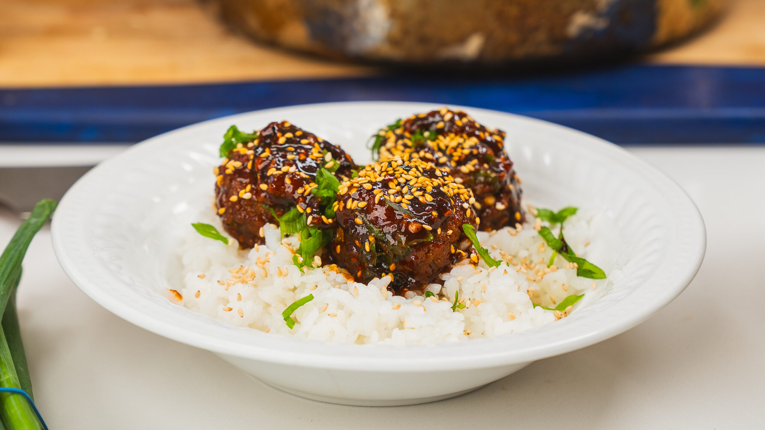 Korean BBQ meatballs served over sticky rice in a white bowl.