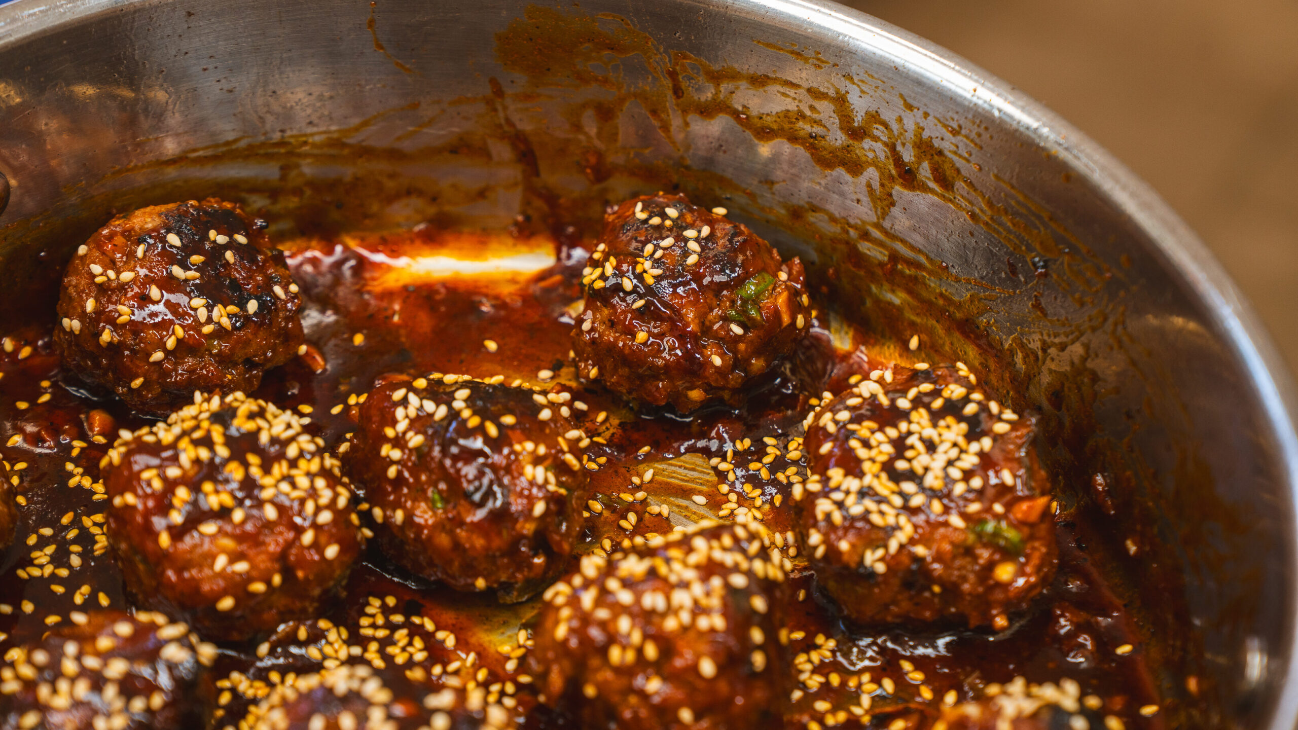 Korean BBQ meatballs simmering in a. pan with a homemade sauce.