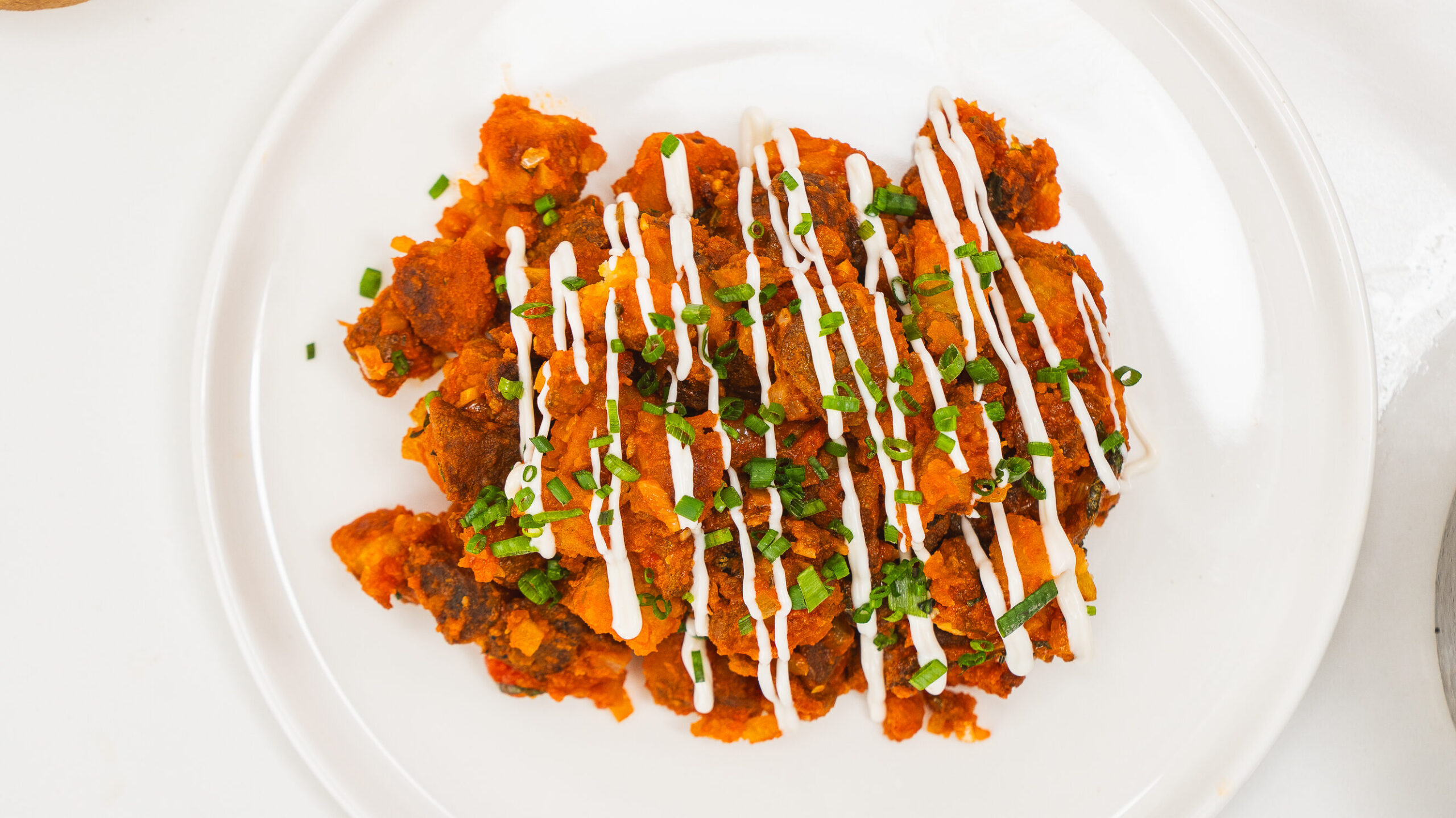 Patatas Bravas with tomato sauce and lemon aioli on a plate.
