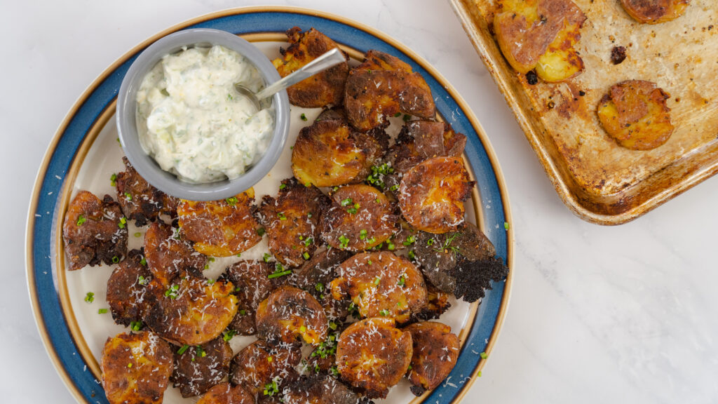 Crispy smashed potatoes with dipping sauce on a plate.
