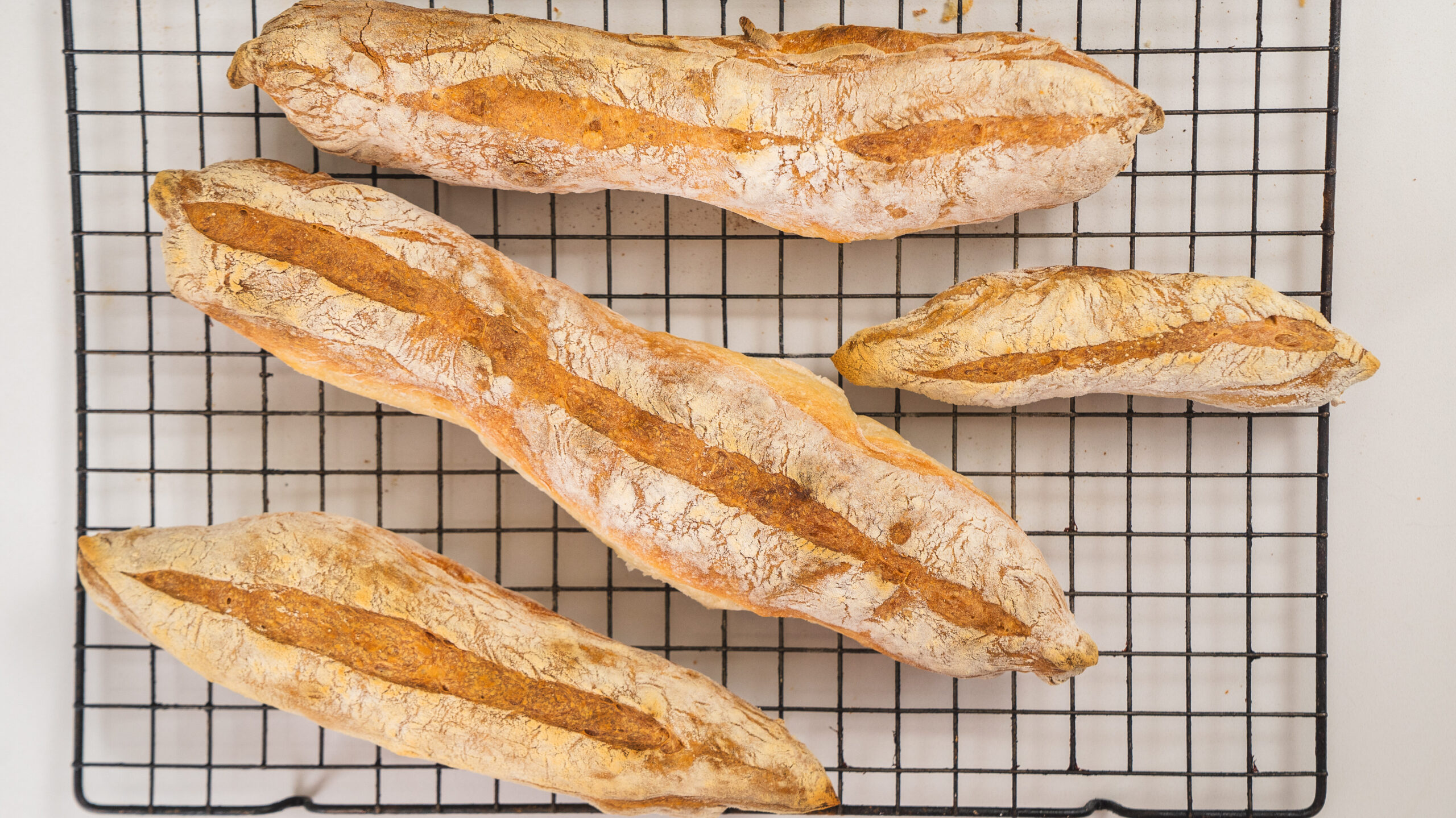 Homemade baguettes on a wire rack.